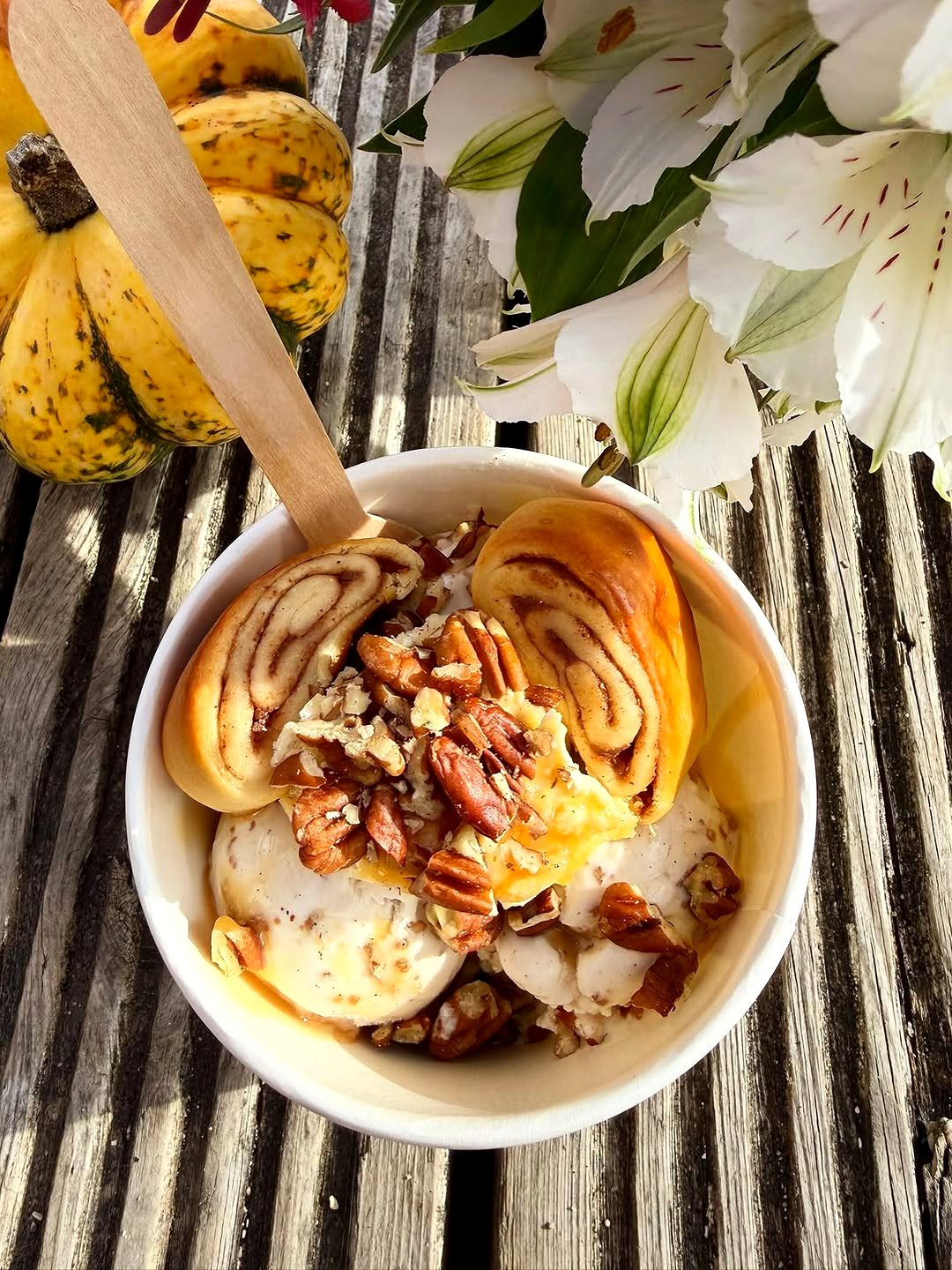 The Cinnamon Bundae: ice cream with clotted cream, toffee sauce, pecans and two mini cinnamon buns, in a paper tub on a wooden table